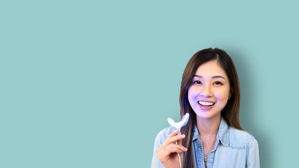 female holding turned on led teeth whitening light